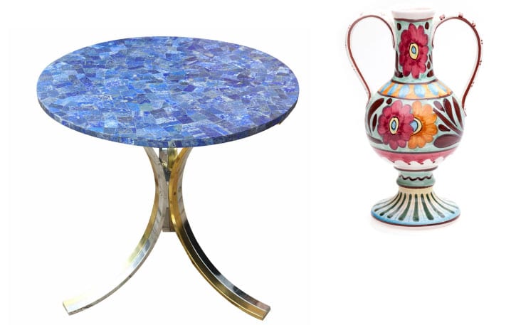 A round table with a blue mosaic top and curving metal legs next to a decorative vase with colorful floral patterns and two handles.